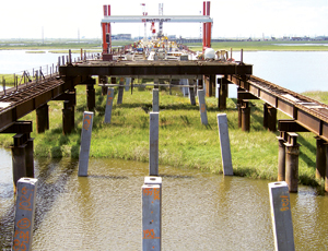Temporary piles support a trestle that serves as a work platform over marshes.