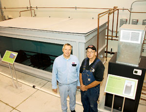 Instructors Paul Chapello (left) and William Wren use 4,000-gallon fish tank to keep geothermal installers in the loop. A nearby ground loop, partially exposed, also is tied into the system.